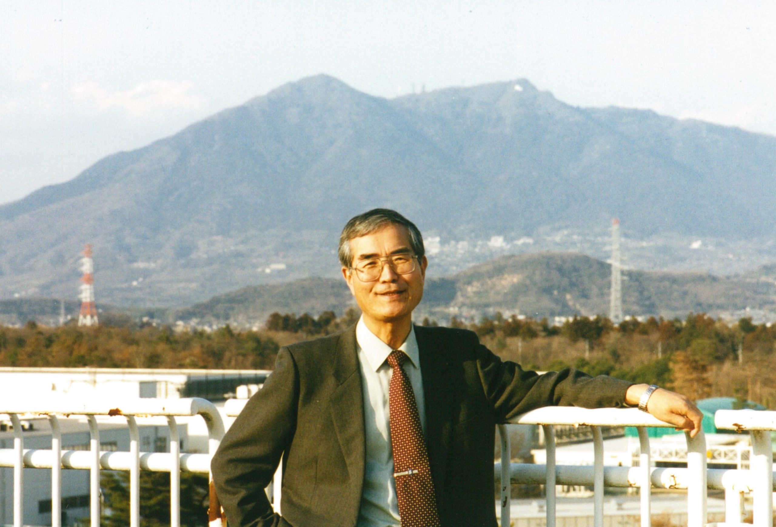 2003年、筑波山の前に立つ戸塚洋二機構長